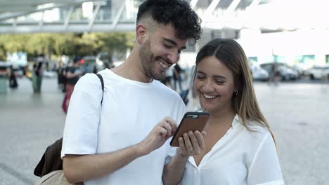 Front-view-of-smiling-young-couple-looking-at-smartphone